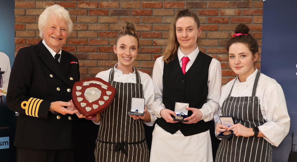 Lady Mary Peters presents Nadia Rainey, Erin Horner and Eimear McCarthy with the winning trophy for the Royal Navy ‘Cook and Serve’ Competition.